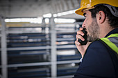 Male supervisor talking, using walkie-talkie in factory