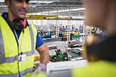 Male workers talking on platform in factory