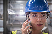 Close up female worker talking on smart phone in factory