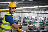 Male supervisor leaning on platform railing in factory