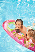 Friends floating on pool raft in summer swimming pool