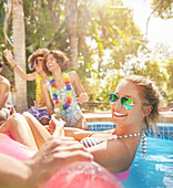 Young woman floating on inflatable raft in swimming pool