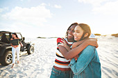 Happy young women friends hugging, enjoying beach road trip