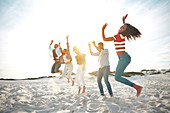 Young friends jumping for joy on sunny summer beach