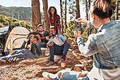 Woman photographing friends hanging out at campsite