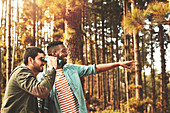 Young men with binoculars bird watching in woods