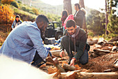 Young men friends building campfire at campsite