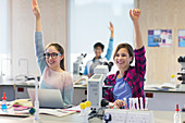 Eager students raising hands in science laboratory classroom