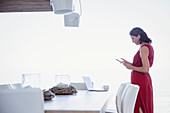 Woman using digital tablet, working at dining room table