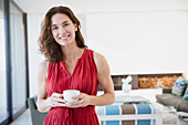 Confident brunette woman drinking coffee in living room