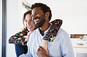 Laughing, affectionate multi-ethnic couple looking away