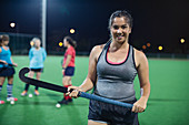 Female field hockey player holding hockey stick on field