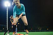 Young female hockey player practicing sports drill on field