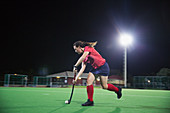 Female hockey player running with hockey stick and ball