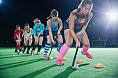 Hockey players practicing sports drill on field at night
