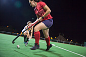 Female hockey players running for the ball