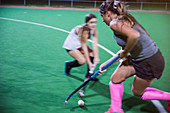 Hockey players reaching for the ball with hockey sticks