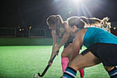 Young female field hockey players reaching for ball