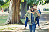 Playful young couple piggybacking in park