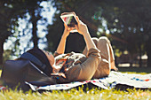 Young woman using digital tablet in sunny summer park
