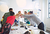 Architects high-fiving in conference room meeting