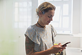 Woman with tattoos texting with smart phone