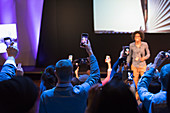Audience members with smart phones videoing speaker on stage