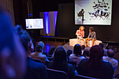 Conference audience watching speakers on stage