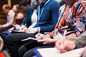 Business people taking notes in conference audience