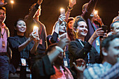 Audience with camera phone flashlights in dark auditorium