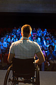 Female speaker in wheelchair on stage talking to audience