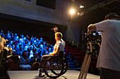 Female speaker in wheelchair on stage waving to audience