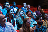 Smiling, enthusiastic audience in dark auditorium