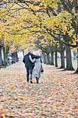 Couple hugging, walking among trees and leaves