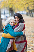 Enthusiastic senior women friends hugging in autumn park