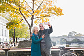 Senior couple taking selfie in front of autumn tree