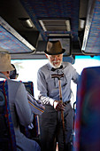 Active senior man in hat with cane boarding tour bus