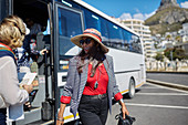 Smiling active senior woman tourist getting off tour bus