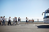 Tour guide leading active senior tourists to tour bus