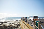 Tourists looking at sunny ocean view outside tour bus