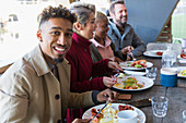 Young man eating breakfast with friends at restaurant