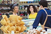 Women talking with worker at bakery display case