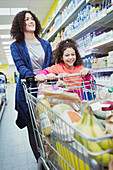 Mother and daughter pushing shopping cart in supermarket