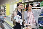 Couple with baby shopping in supermarket