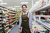 Smiling confident female grocer working in supermarket