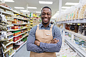 Confident smiling male grocer working in supermarket