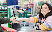 Cashier giving receipt to customer at supermarket checkout
