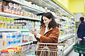 Smiling woman reading label on container in supermarket