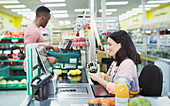 Cashier helping customer at supermarket checkout