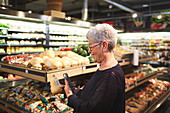 Senior woman shopping in supermarket produce section